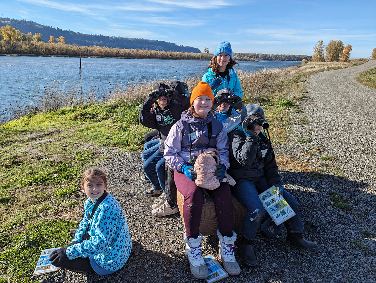 a group of students sit on a rock by the Columbia River