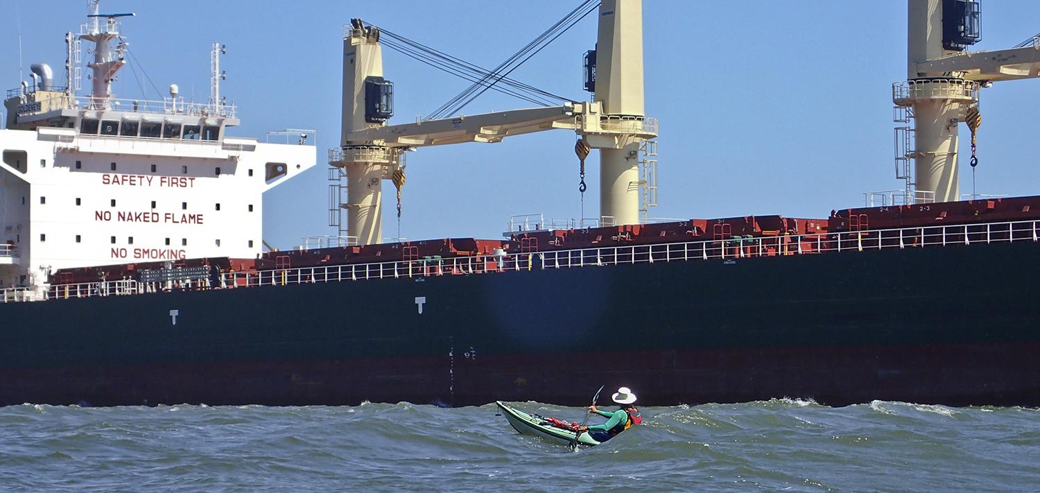 Ginni kayaks alongside a giant tanker, the Goldeneye