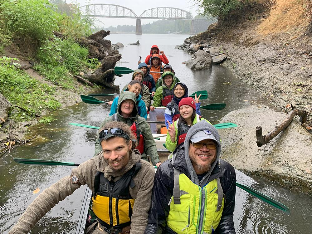 a group of smiling people in the rain on a canoe