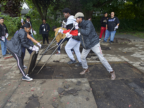 a group of volunteers pries up a 4x4 slab of concrete