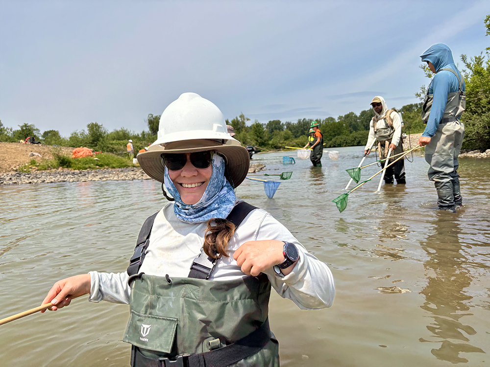 volunteer in waders holding a fish net