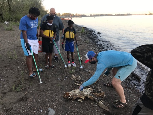 EP educator and Blueprint youth examine a sturgeon skeleton on the beach