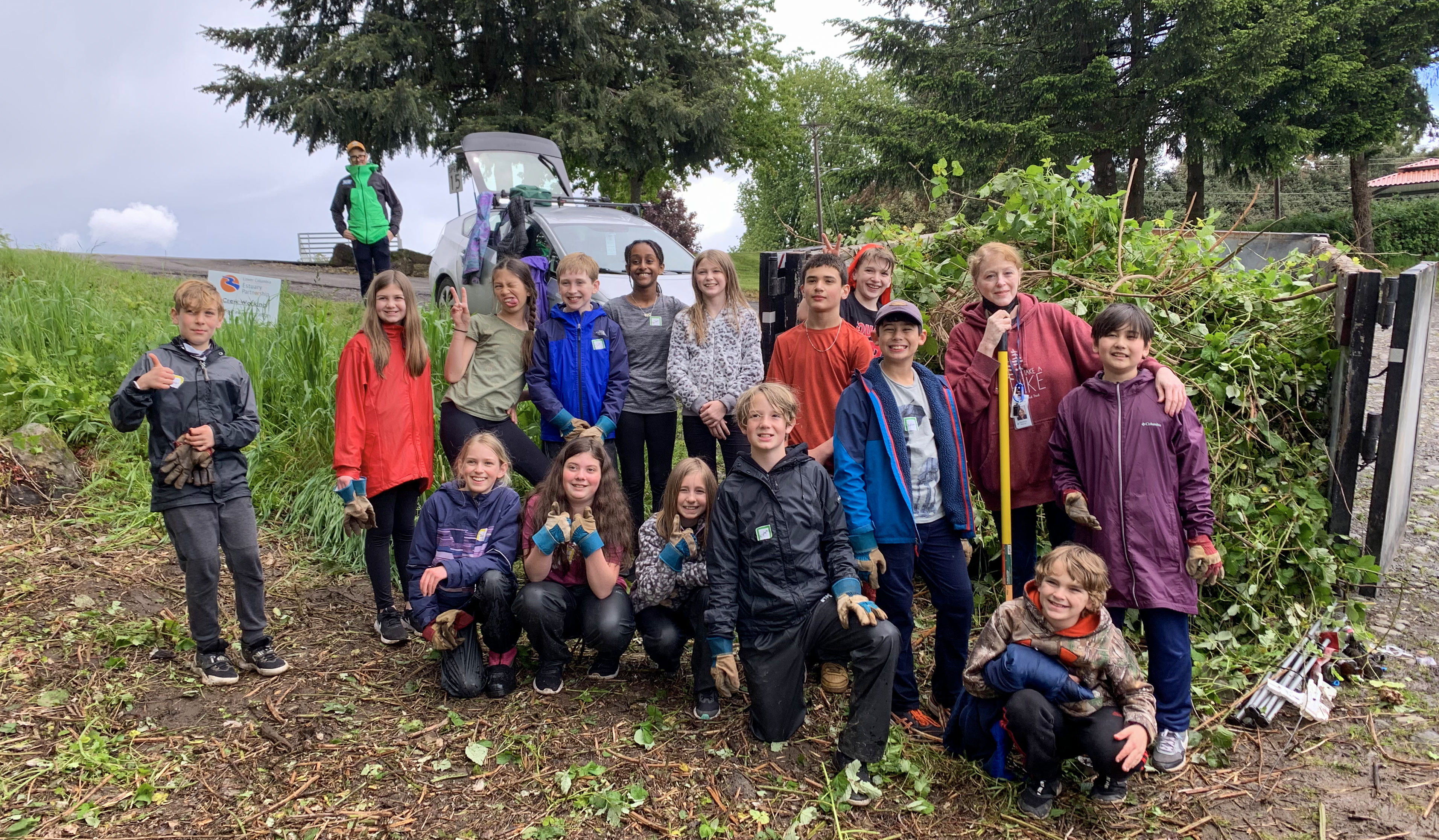 students standing near pile of ivy and blackberry debris they removed