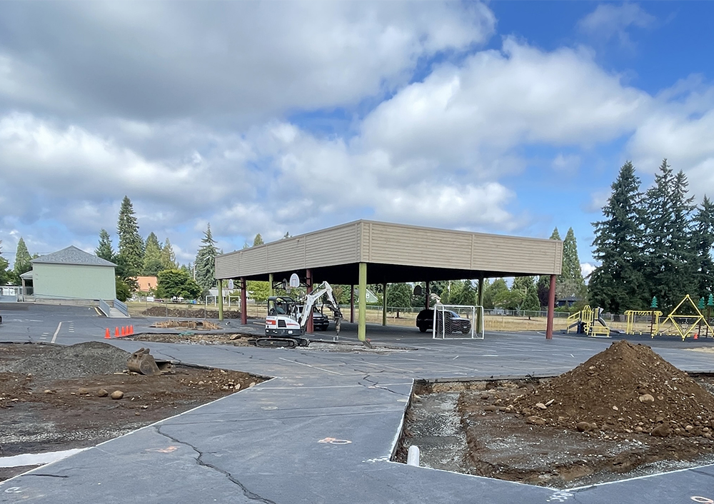 areas of removed pavement in the middle of a parking lot with a bulldozer