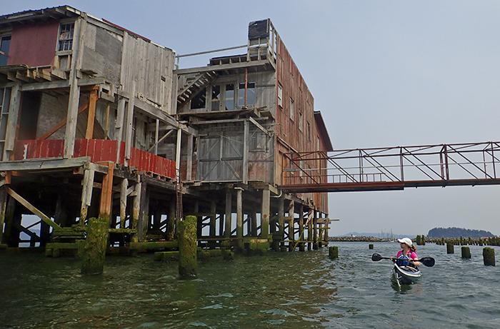 kayaker by decaying building set up on pilings