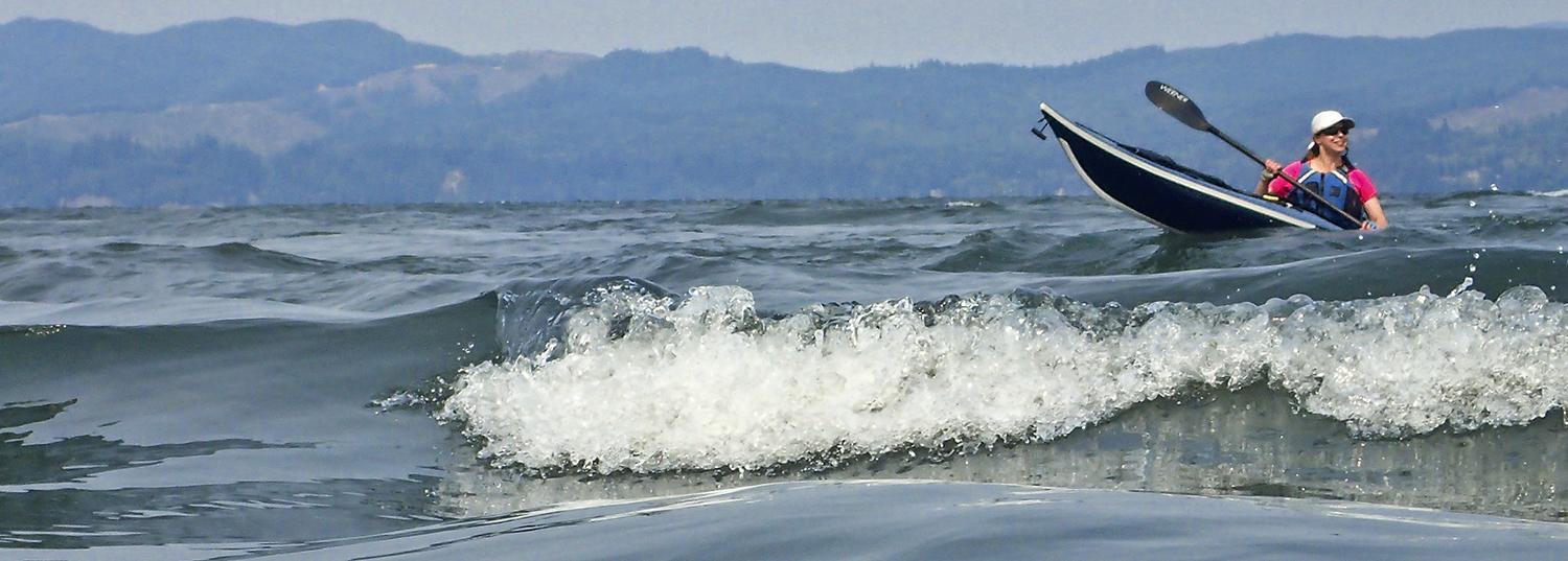 kayaker smiles as she surfs a wave in the Columbia