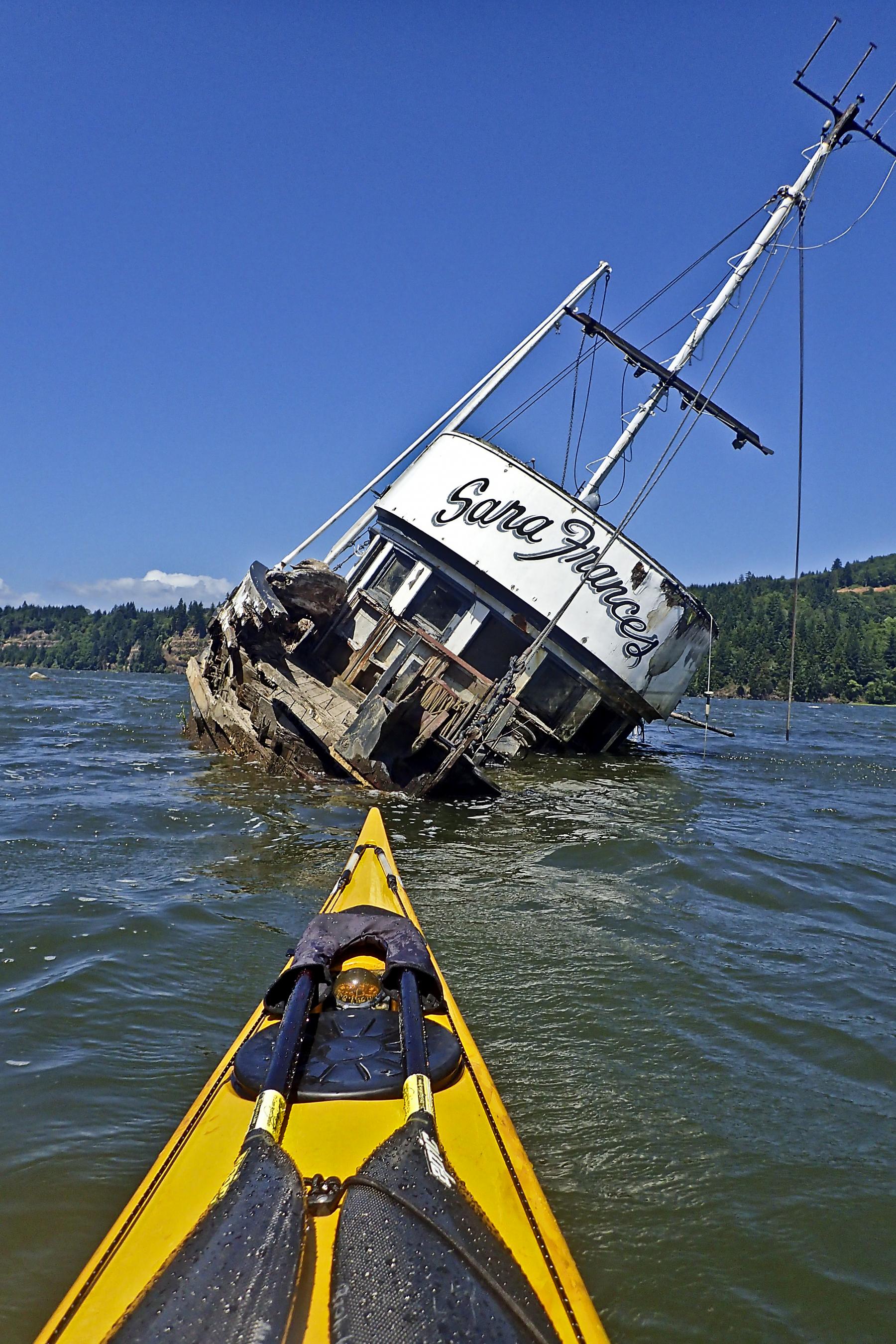 kayak bow faces a half-sunken ship, named the Sarah Frances