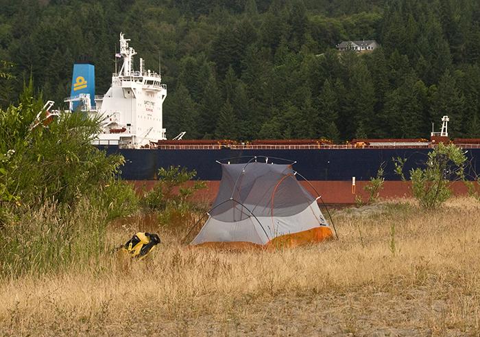 tent on Quill Island with large barge passing in the background