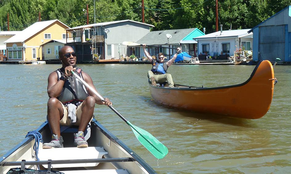 two people canoe near floating homes on Vancouver Lake