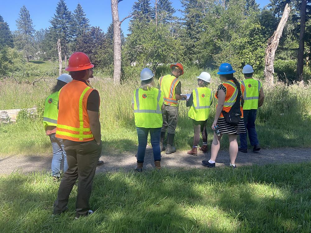 a group of people in safety vests and hard hats examine a map