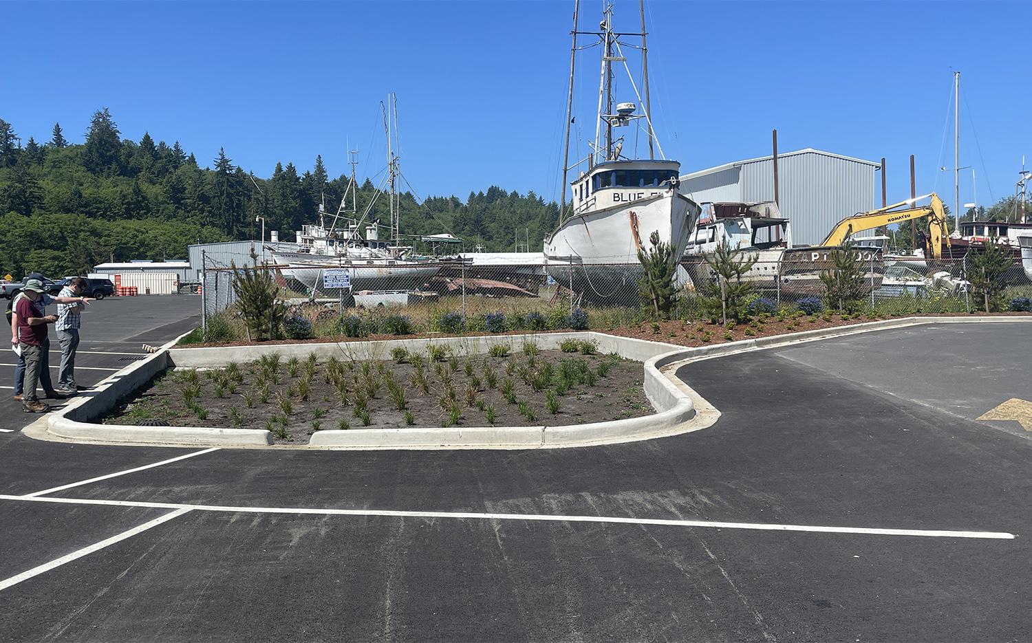 three people look at a new biofiltration facility. A large sailboat is in the background