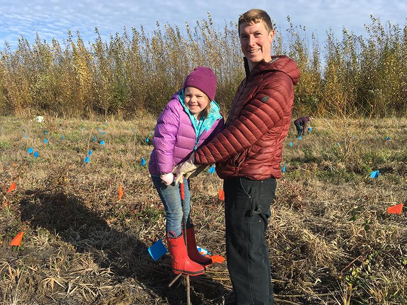 a father helps his daughter stand on a planting bar