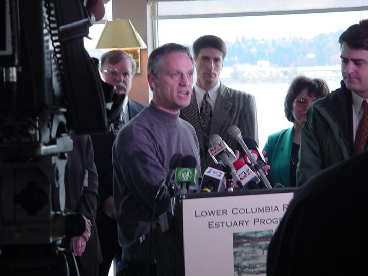 Congressman Blumenauer speaks at a podium with many news station mics