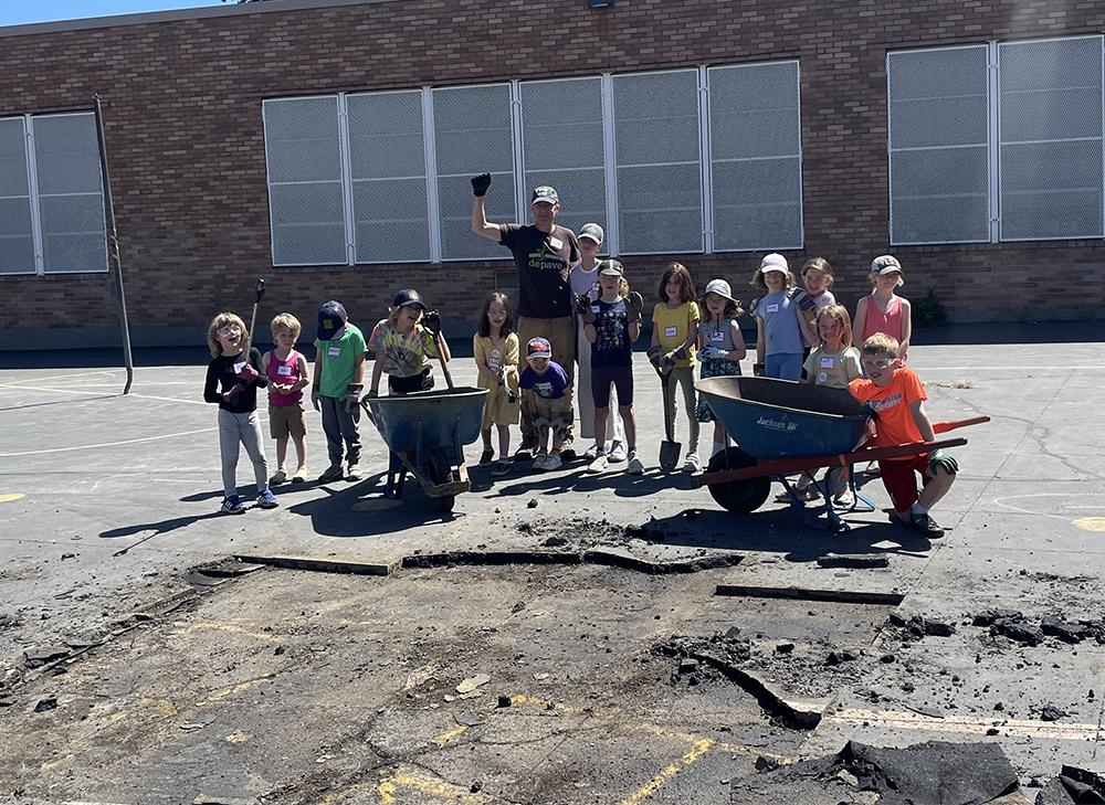 a group of young students with work gloves and goggles stand behind a depaved area