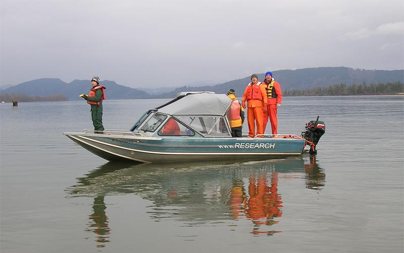 People stand on a research boat on the Columbia River