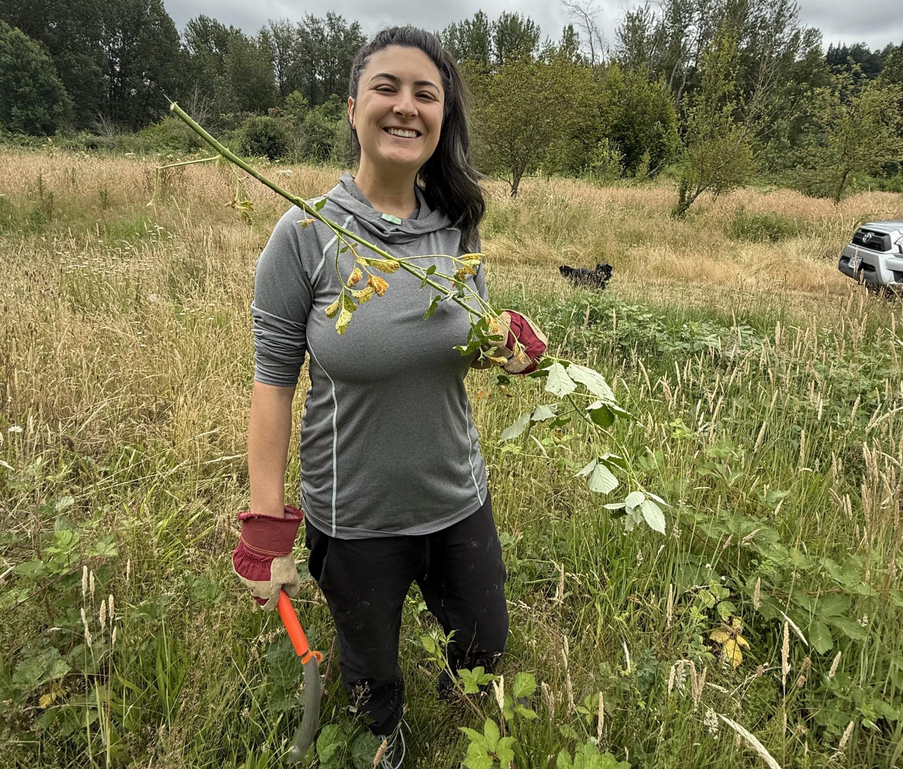 a smiling volunteer holds a blackberry cane and clippers