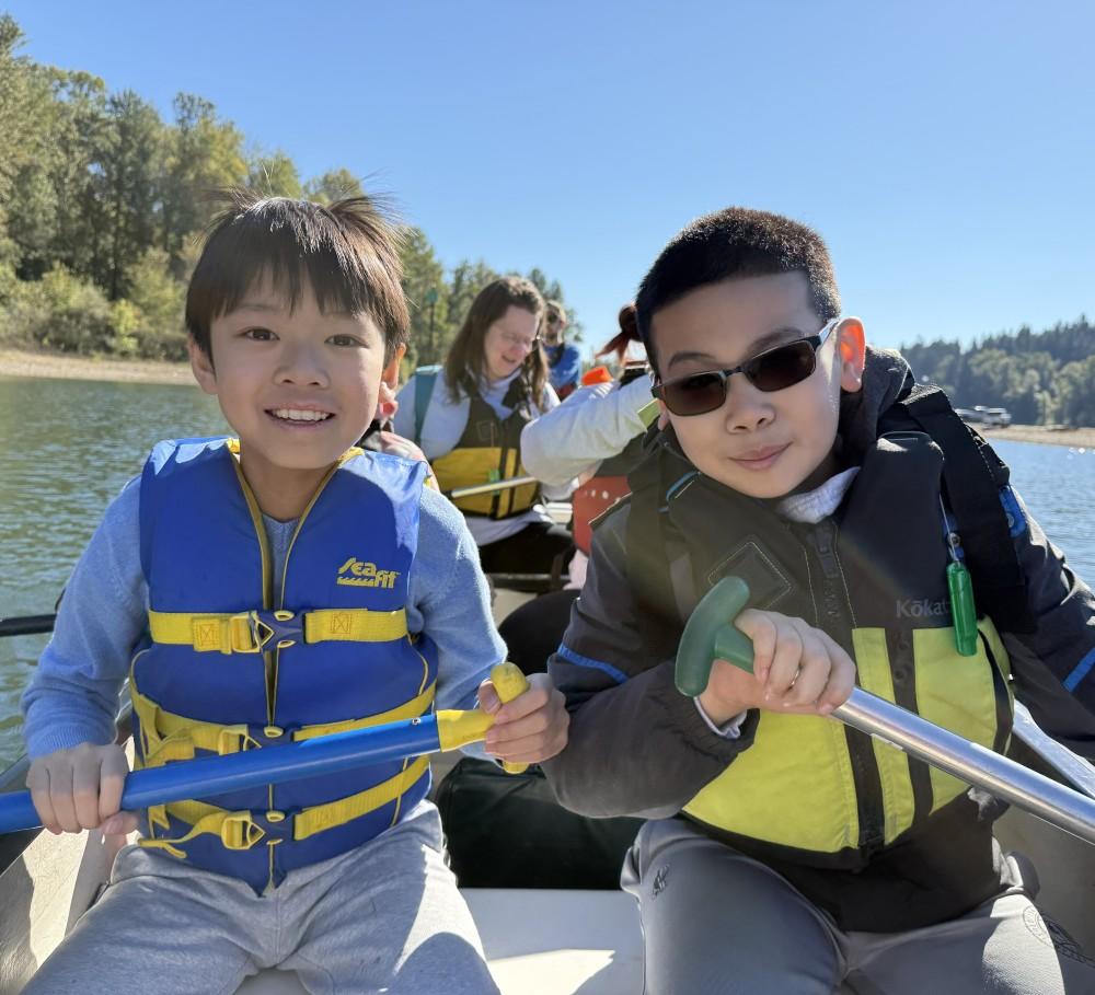 two students hold paddles in the front of a Big Canoe