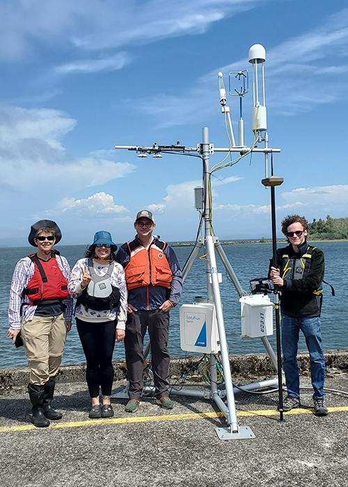 a group of 4 folks in life jackets stand by an Eddy Flux tower on a pier over the Columbia River