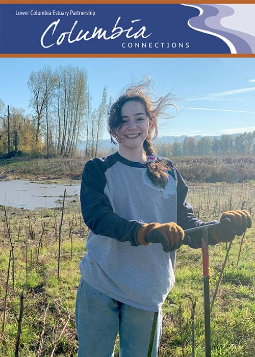A young person pauses from planting trees to smile