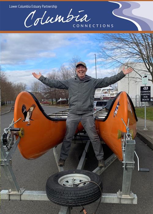 A person stands triiumphantly on a trailer between two canoes