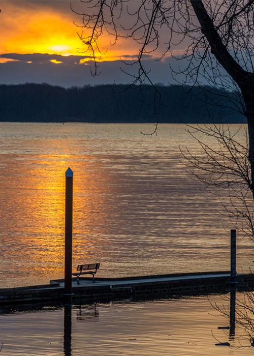 The Columbia River at sunset. A dock with a bench is in the foreground